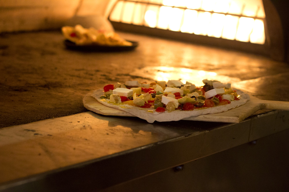 Skilled pizza chef preparing craft pizza in professional kitchen